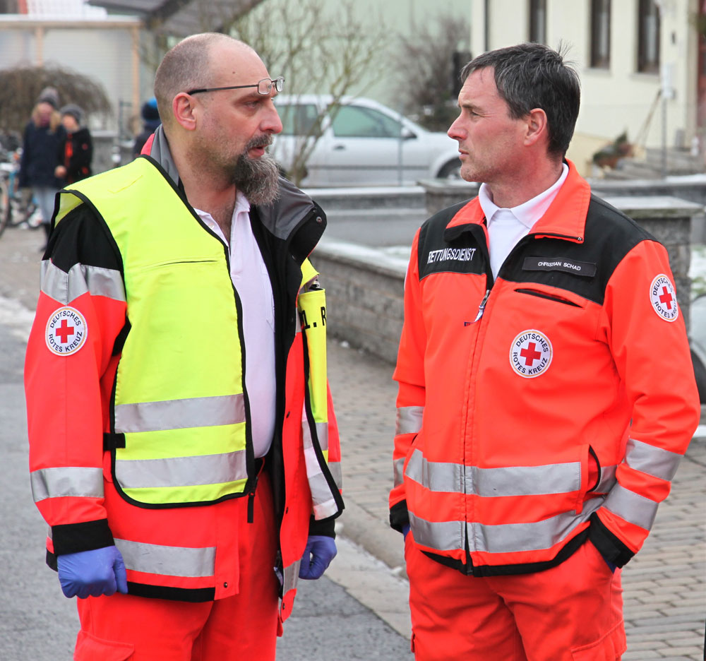 Notfallsanitäter Jürgen Bäuerlein (links), der Leiter der BRK-Rettugswache Eltmann ist, schätzte die gefährliche Situation an der Einsatzstelle sofort richtig ein und handelte professionell. Zusammen mit seinem Kollegen und einem Ersthelfer gelang es ihm, alle Patienten rechtzeitig aus dem Gefahrenbereich ins Freie zu bringen. Hier ist er im Gespräch mit seinem Kollegen Christian Schad (rechts) von BRK aus Gerolzhofen. (Foto: Michael Will / BRK)